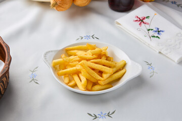 Golden Crispy French Fries on Elegant Embroidered Tablecloth with Soft, Warm Lighting