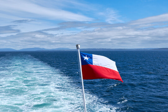 Chilean flag waving on the stern of a ship with the wake of navigation in the background