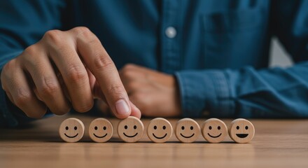 A Hand Carefully Selects A Happy Face From A Row Of Wooden Emotion Icons, Signifying The Pursuit Of Positive Customer Feedback And Satisfaction On A Warm Wooden Table