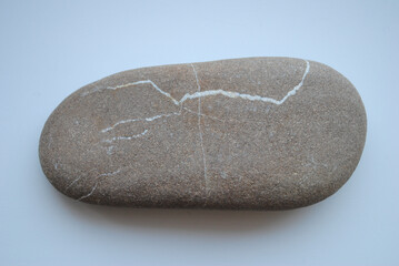 Smooth oval stone with white natural veins on a light background. Minimalist and organic design, showcasing natural beauty and geological patterns.