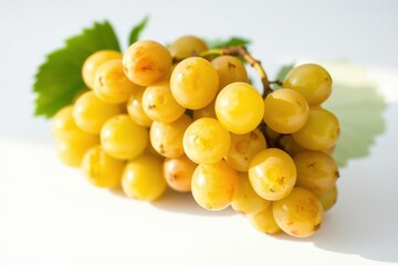Fresh yellow grapes on a white surface