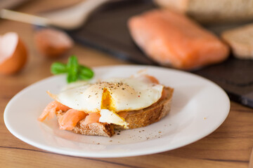 A slice of bread with lightly salted red fish and a cooked egg for breakfast