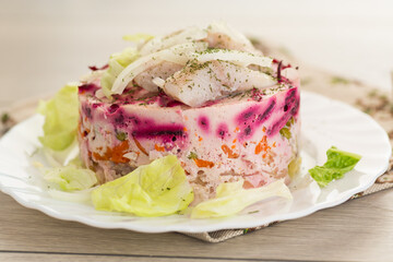 layered vegetable salad with beets and herring, on a wooden table