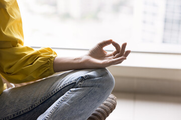Close up cropped view woman sits in lotus position doing meditation, practice of self-awareness...