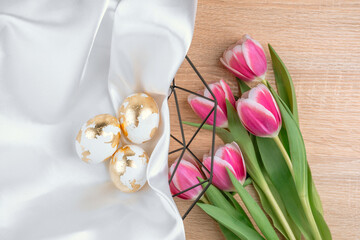 Gold Easter eggs in a basket with pink tulips, top view. Easter backgorund.