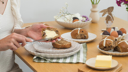 Woman smearing butter on Hot Cross Buns. Happy Easter