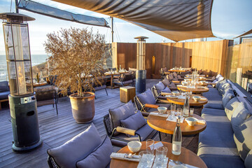 Cozy open-air restaurant on the Atlantic ocean shore. Gas heaters in restaurant overlooking the sea