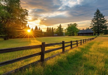 Fototapeta premium Serene Sunrise Over Farm Field with Wooden Fence and Rustic Cabin Amid Lush Green Landscape and Sunlight Breaking Through Clouds