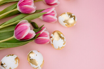 Easter gold eggs with tulips on a pastel pink background.