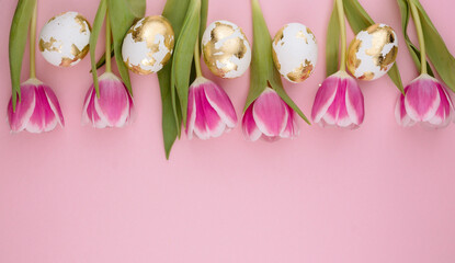 Easter gold eggs with tulips on a pastel pink background. Copy space.