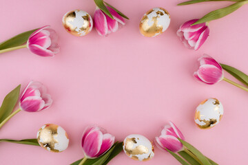 Easter gold eggs with tulips on a pastel pink background. Copy space.