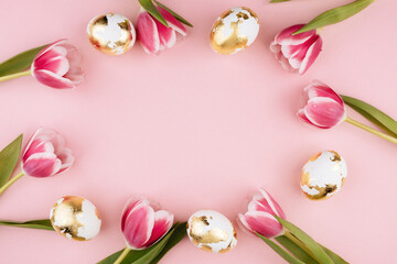 Easter gold eggs with tulips on a pastel pink background. Copy space.