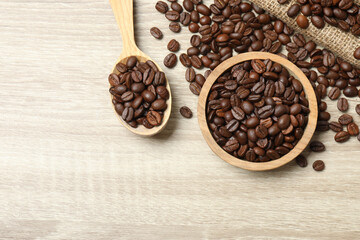 Bowl and spoon with coffee beans on wooden background