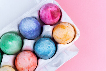 Colourful Easter eggs in a carton box top view. Easter background.