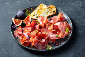 Charcuterie with fresh figs and ciabatta toasts. Dark background. Close up.