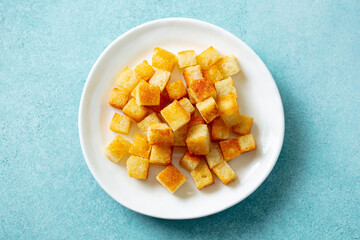 Croutons on a white plate. Blue background. Close up. Top view.