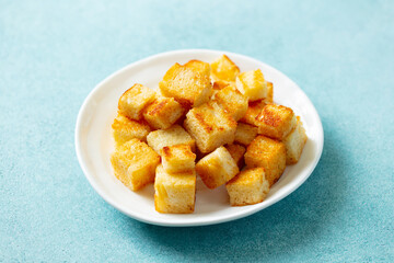 Croutons on a white plate. Blue background. Close up.