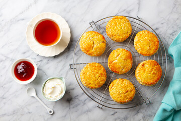 Scones, tea cakes with jam, clotted cream with tea. Marble background. Close up. Top view.