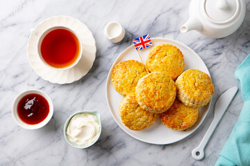Scones, tea cakes with jam, clotted cream with the flag of Great Britain. Marble background. Close up. Top view.