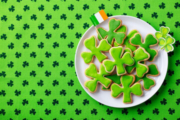 Clover cookies with Irish flag, St. Patrick's Day dessert. Green textile background. Copy space....