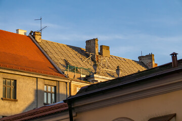 replacing the roof on an old tenement house. repairing the roof on a residential building in the city. renovation of a tenement house. buildings against the background of a blue sky.