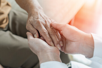 Arthritis or parkinson disease elderly patient, old aged senior woman holding geriatric doctor, cargiving nurse or family assistant's hand in hospice home for medical health care or mental therapy