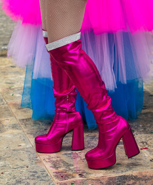 Close-up low section of a woman wearing pink platform knee high boots at a carnival