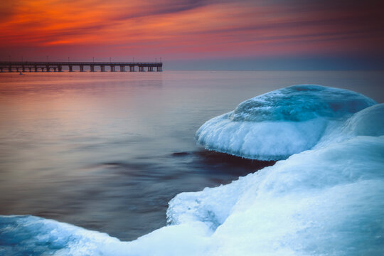 Icy coastline with Palanga Pier in the distance at sunset, Klaipeda, Lithuania