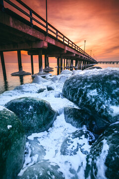 Snow covered rocks by Palanga Pier at sunset, Klaipeda, Lithuania