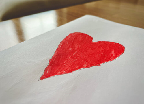 Close-up of a child's drawing of a red heart on a wooden table