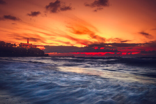 Dramatic orange sunset over beach and Old Jaffa, Tel Aviv, Israel