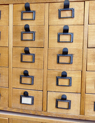 Old vintage wooden drawer cabinet with metal plate handles for archive or catalog organization.