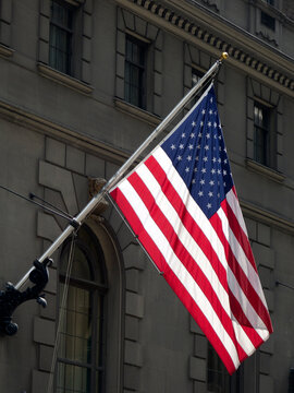 Close-up of an American flag hanging on a flagpole outside a building, New York, USA