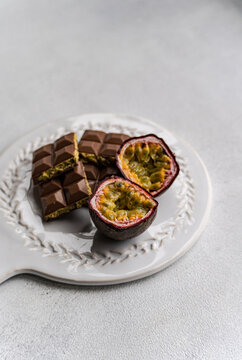 Close-up of a Dubai chocolate bar filled with pistachio paste next to fresh passion fruit on a serving plate