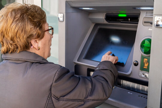 Elderly woman using the ATM in the city.