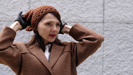 A woman adjusts her outfit thoughtfully, exuding confidence and comfort in the cool weather.