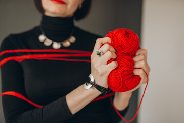 Woman's Hands Holding a Red Yarn Ball with Threads Wrapped Around
