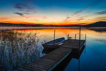 Obraz premium Morning serenity at a lake in Sweden with a tranquil dock and colorful sunrise reflections
