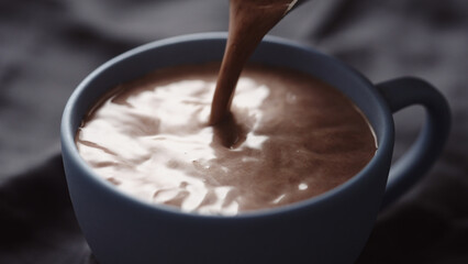 pour hot chocolate into blue cup closeup