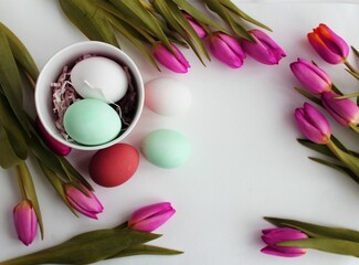 Easter still life with eggs and tulips on a white background. View from above.