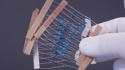 Close-up of a THT 1/4W resistor with a color-coded band pattern, positioned on a dark background. A...