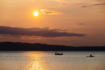 Dinghy passing in front of Cres island, Croatia with istrian peninsula rising in the background during wonderful, golden hour