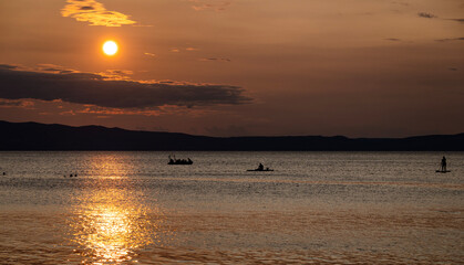 People enjoying sunset on Cres island, Croatia, swimming and  paddling on the sup boards