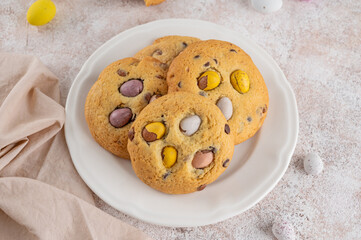 Easter cookies. Tradition american cookies with chocolate mini eggs candy on a white plate. Easter dessert. Copy space.