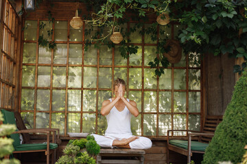 Blonde man doing yoga on the veranda in garden at backyard