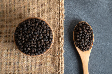 A bowl and a spoon with black peppercorns,top view
