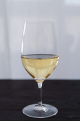 White wine in a wineglass on black oak table with copy space