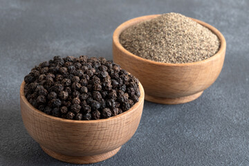 Ground black pepper with grains of black pepper on gray background