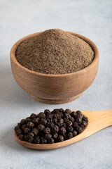 Ground black pepper with grains of black pepper on light background