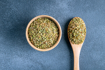 A bowl full of dried and ground natural mountain thyme on anthracite background